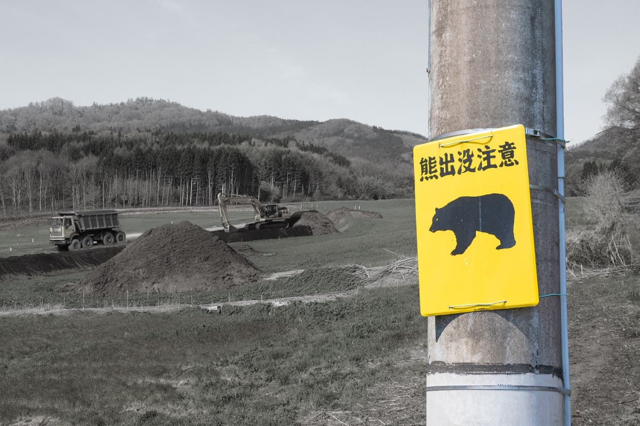クマ出没注意の看板と山間部の工事現場